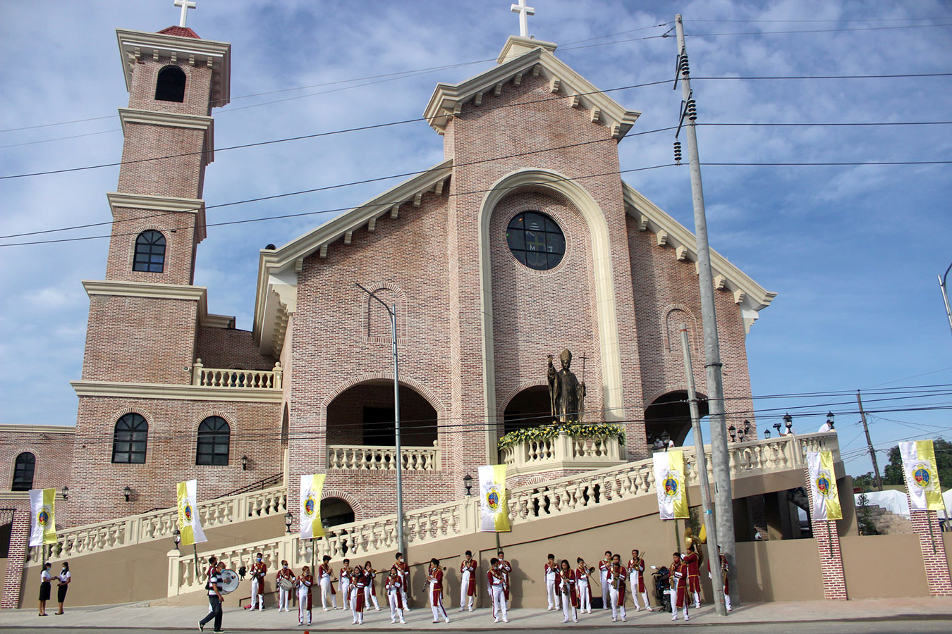 Front of the National Shrine and Parish of St. John Paul II, a brick church with a tall bell tower and a statue of St. John Paul II above the main entrance